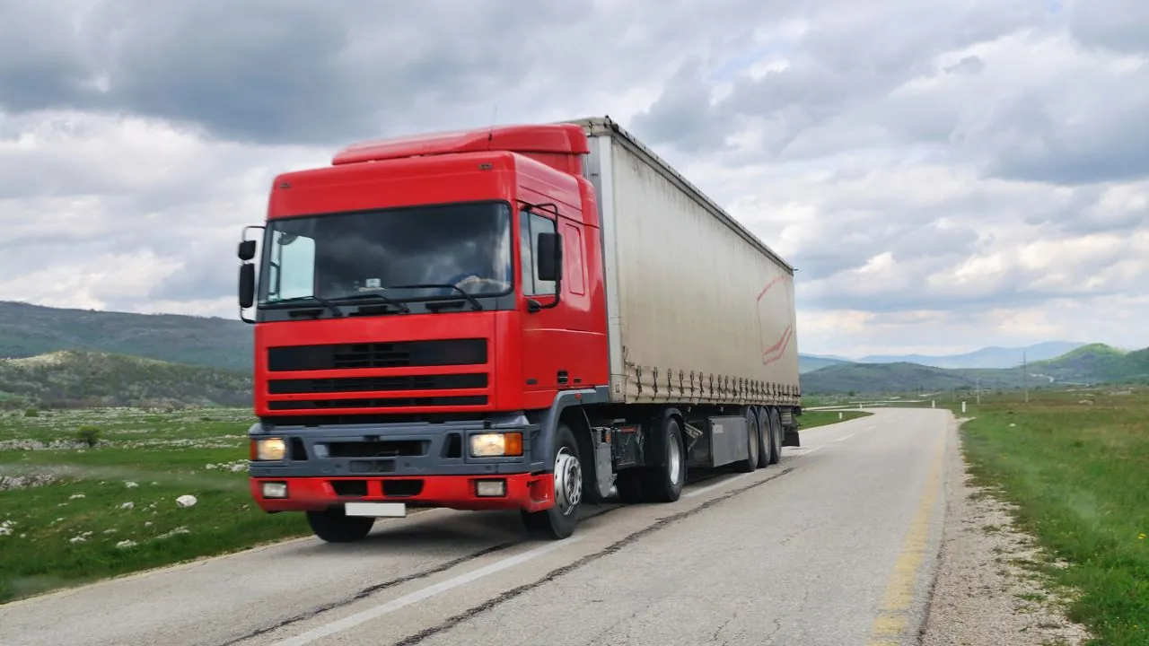 Caminhão vermelho com carreta em rodovia